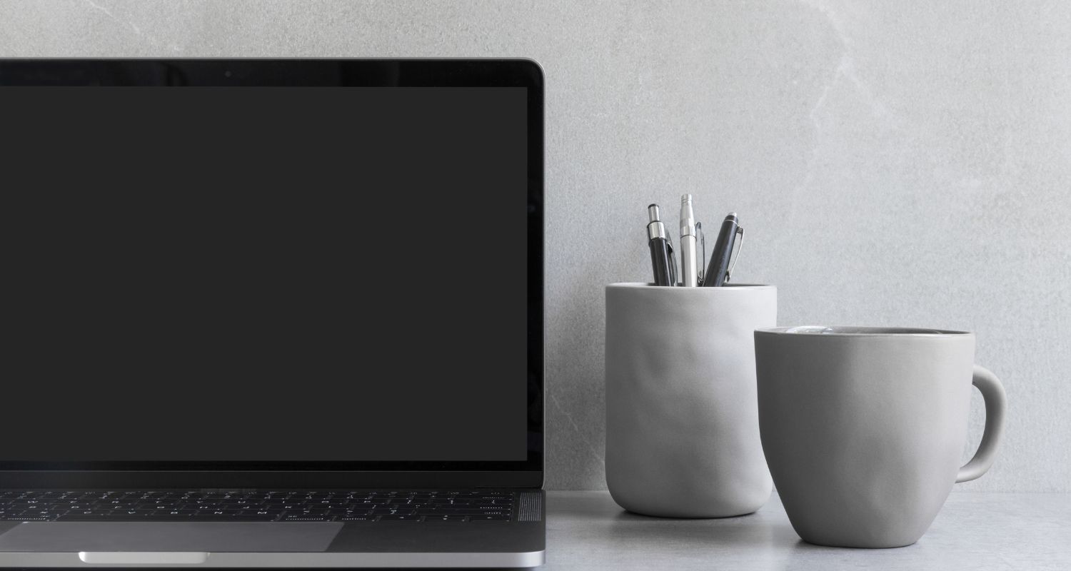 A laptop with a grey mug