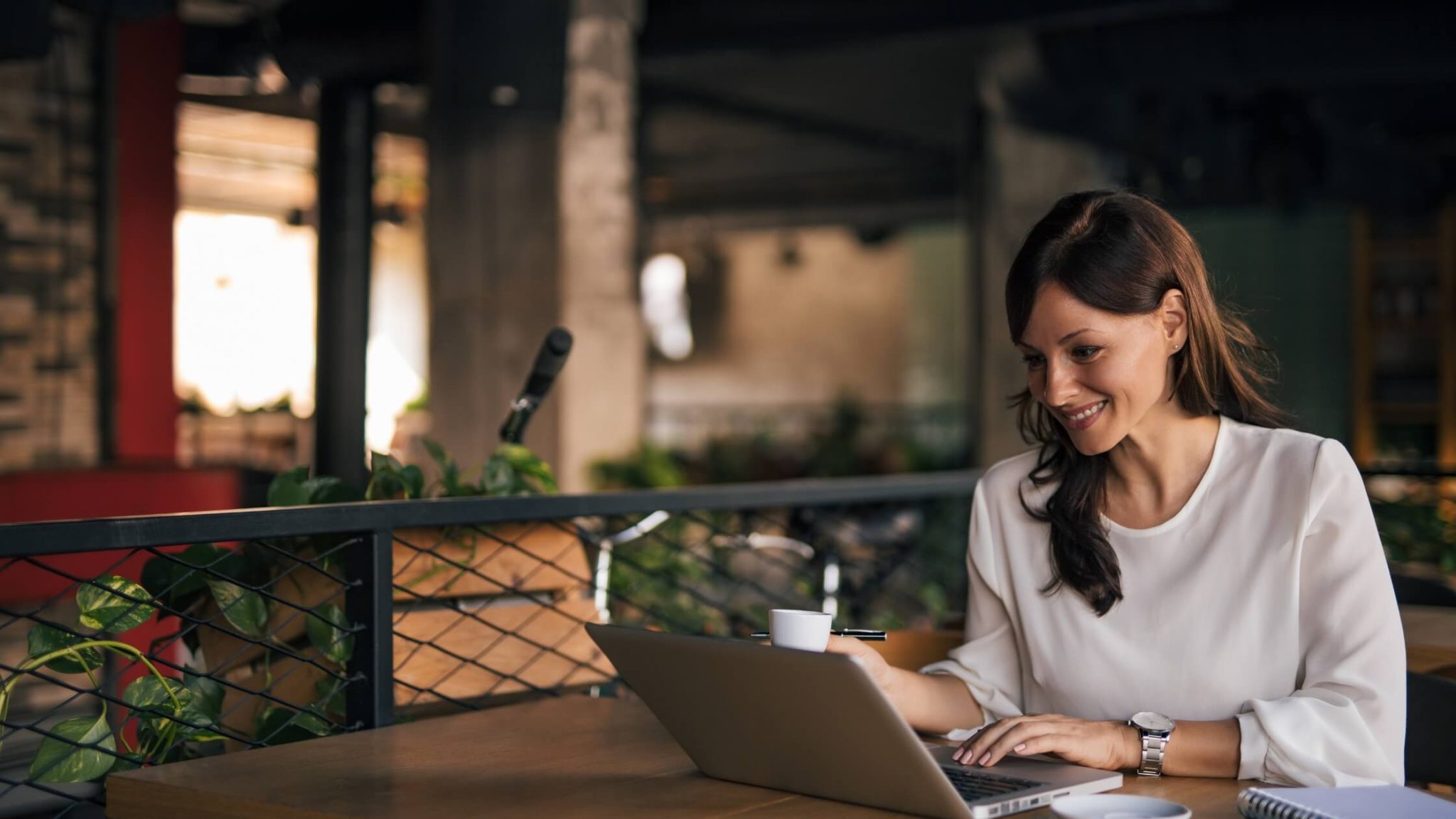 Well-dressed woman working with her laptop outdoors in a warm and dark environment.