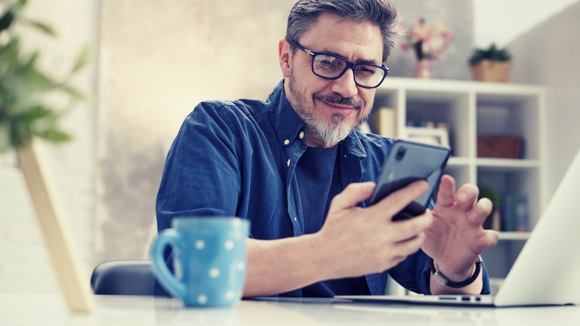 Business man with glasses, over 45 years old, checking his cell phone and smiling.