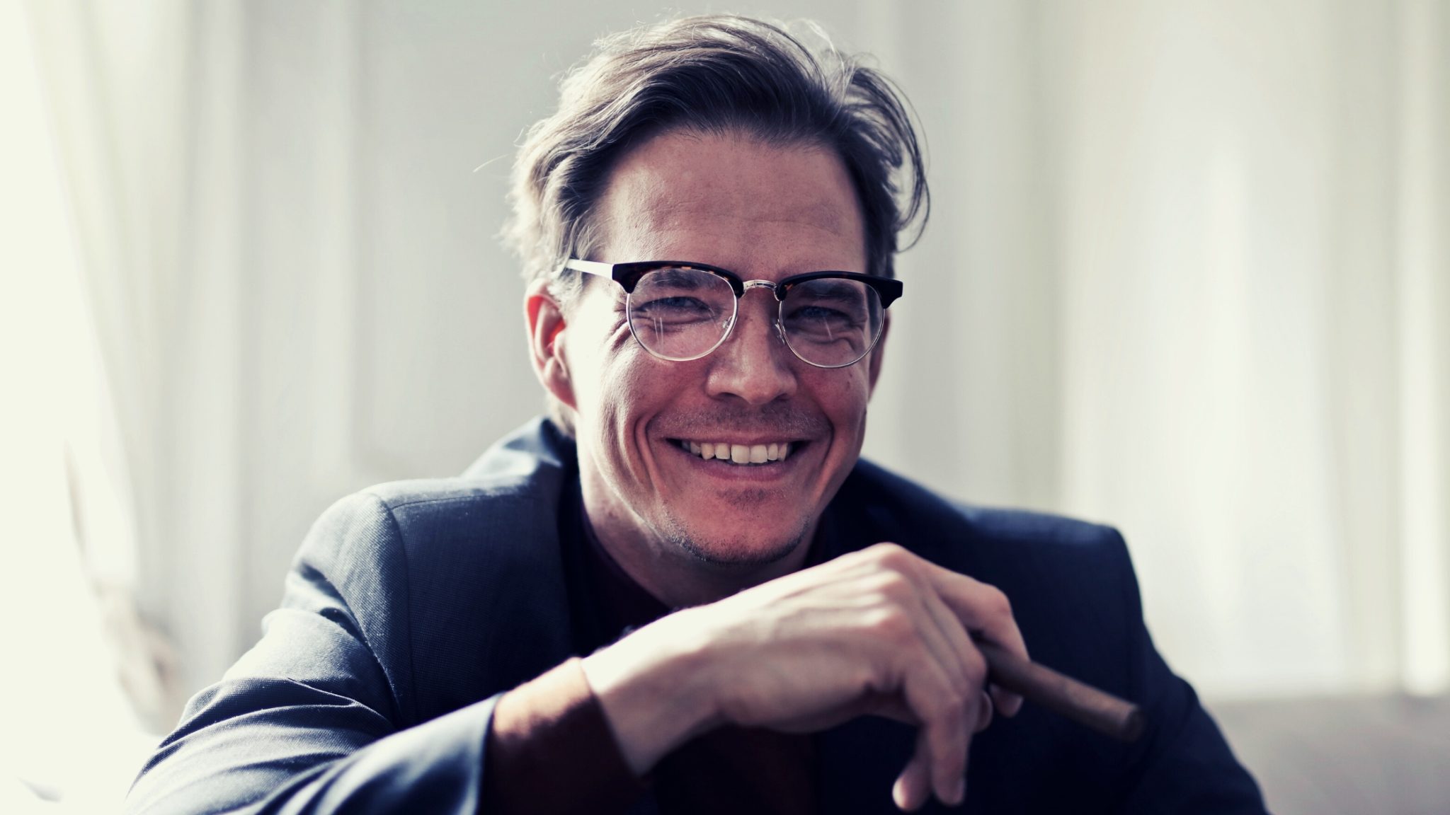 Male business coach, over 40 years old, wearing glasses and smiling.