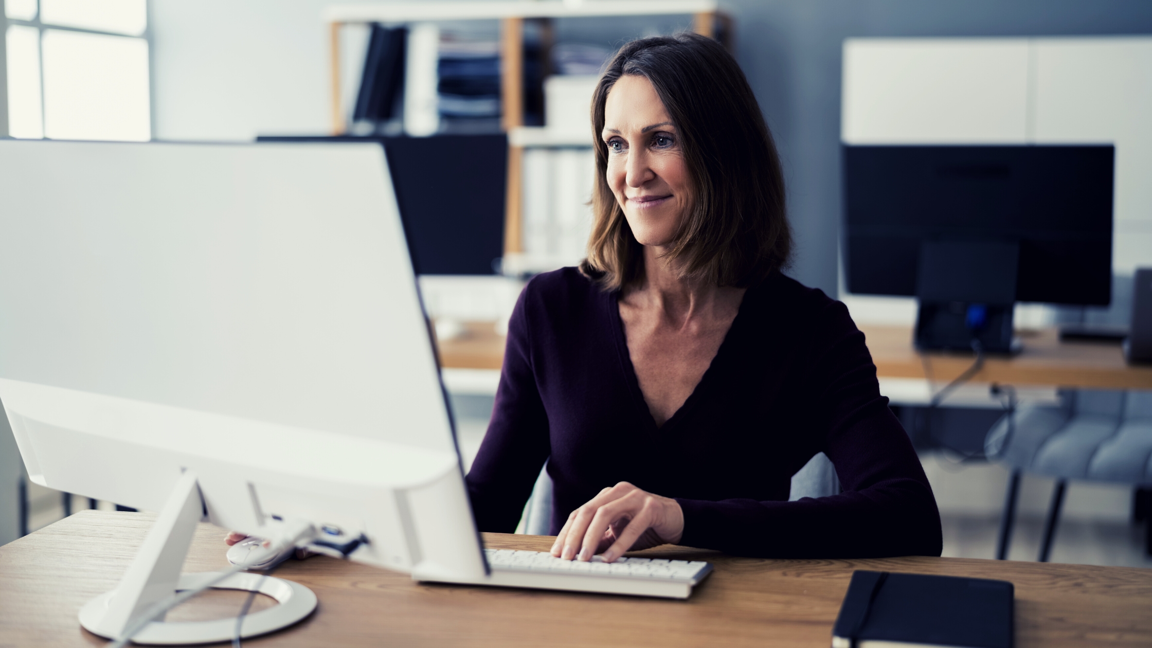 Business coach woman looking at her computer and sending an email to her Virtual Assistant for Coaches from Delegate First