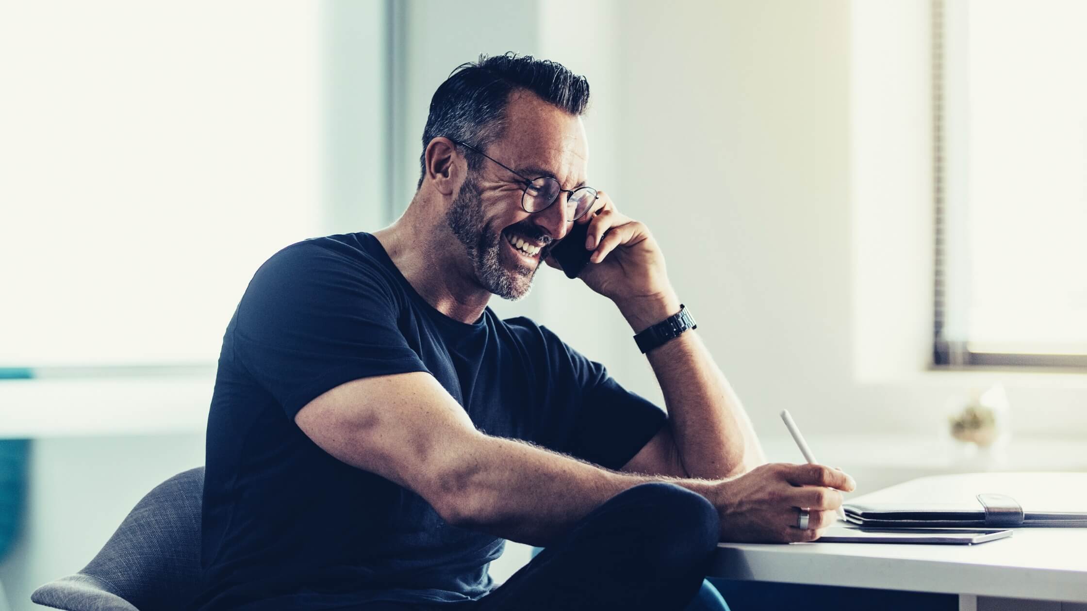 male-business-coach-marketing-for-coaches Smiling male business coach on phone call, representing professional support and strategies in marketing for coaches